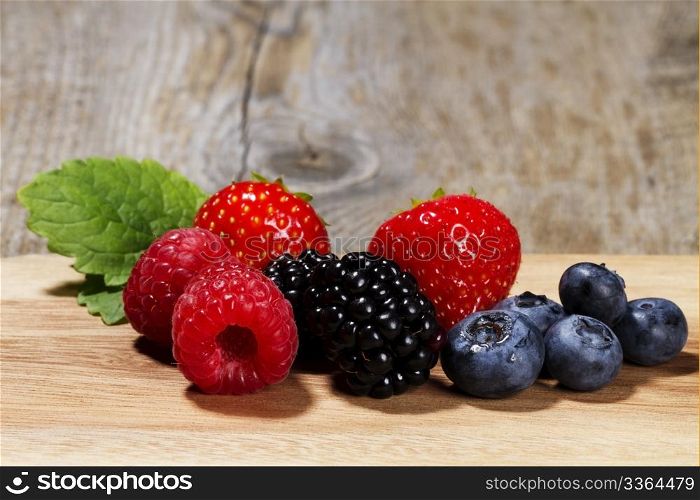 wild berries on wooden background. wild berries on a chopping board on wooden background