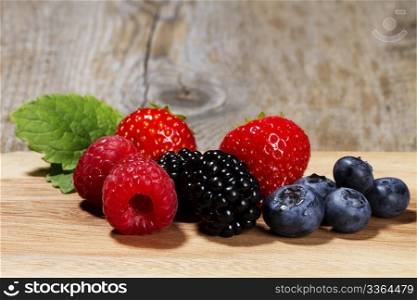 wild berries on wooden background. wild berries on a chopping board on wooden background