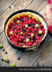 Wild berry homemade pie with fresh raspberries and blueberries on wooden rustic background