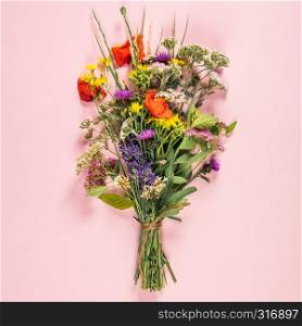 Wild flower bouquet on pastel color background. Top view, flat lay