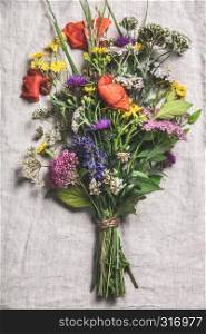 Wild flower bouquet on vintage linen background. Top view, flat lay