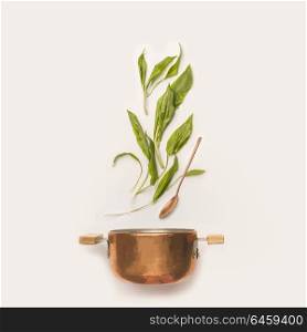 Wild garlic leaves and cooking pot with spoon on white background. Healthy seasonal food and eating concept