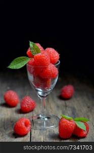 Wild raspberry in small glass and  leaves in studio