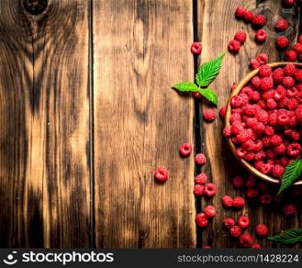 Wild raspberry with leaves in a bowl. On a wooden table.. Wild raspberry with leaves in a bowl.