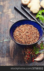 wild rice in ceramic bowl and asian ingredients on wooden background