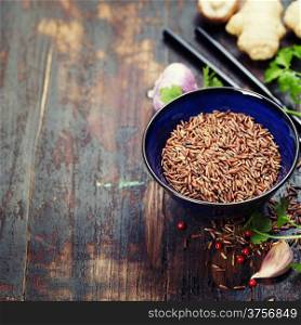 wild rice in ceramic bowl and asian ingredients on wooden background