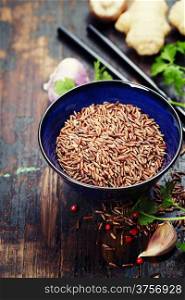 wild rice in ceramic bowl and asian ingredients on wooden background