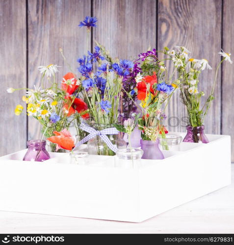 Wildflowers in bottles in the box. Kitchen flowers decor