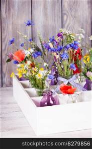 Wildflowers in bottles in the box. Kitchen flowers decor