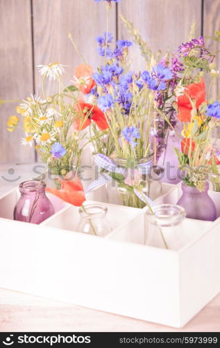 Wildflowers in bottles in the box. Kitchen flowers decor. Wildflowers in bottles