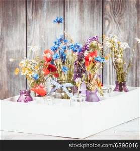 Wildflowers in bottles in the box. Kitchen flowers decor. Wildflowers in bottles