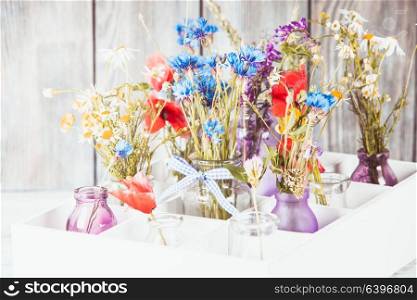 Wildflowers in bottles in the box. Kitchen flowers decor. Wildflowers in bottles