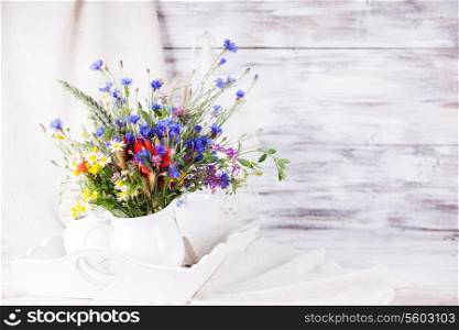Wildflowers in white ceramic jug and cups on tray with copy space