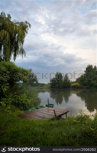 Wildlife, pier with a boat with oars. The sky after the rain, freshness in the air. The concept of c&ing and country rest with tents. Wildlife, pier with a boat with oars. The sky after the rain, freshness in the air. The concept of c&ing and country rest with tents.