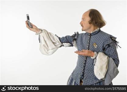 William Shakespeare in period clothing holding cell phone and gesturing.