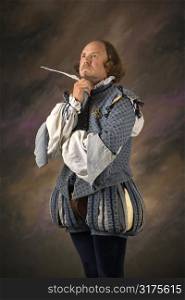 William Shakespeare in period clothing holding feather pen with thoughtful expression.