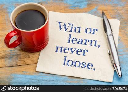 Win or learn, never loose - handwriting on a napkin with a cup of espresso coffee