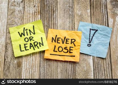 Win or learn, never loose - reminder on sticky notes against a grunge wood