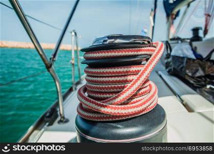 Winch with red and white rope on sailing boat in the sea.