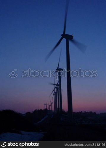 Wind farm in silhouette at sunset, nice blue sky in background