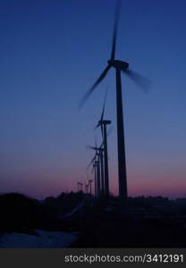 Wind farm in silhouette at sunset, nice blue sky in background