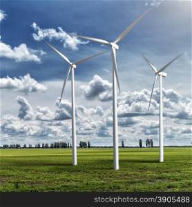 Wind generators turbines on summer landscape under blue sky and clouds