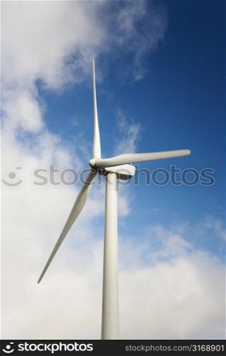 Wind turbine against blue sky and clouds.