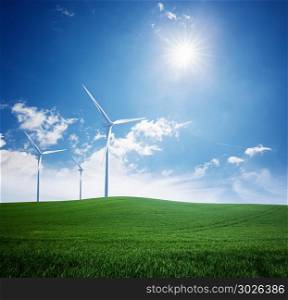 Wind turbine at the green grass field over blue sky. Wind turbine and green field. Wind turbine and green field