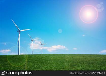 Wind turbine at the green grass field over blue sunny sky. Wind turbine and green field. Wind turbine and green field
