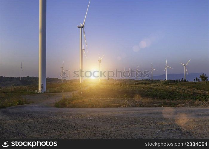 Wind turbine farm at sunset sky background. Wind power renewable energy concept.