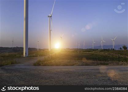 Wind turbine farm at sunset sky background. Wind power renewable energy concept.