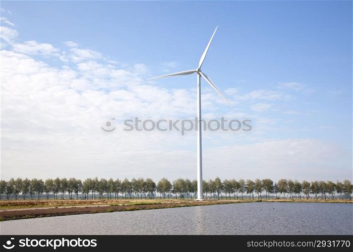 wind turbine next to lake and row of trees in holland