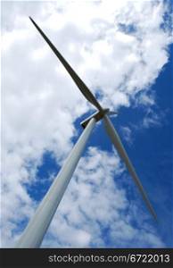 Wind turbine on blue and cloudy sky in vertical view. Wind turbine on cloudy sky