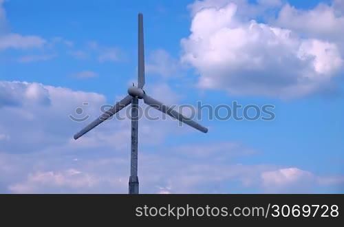 wind turbine rotates continuously on a background cloudy sky