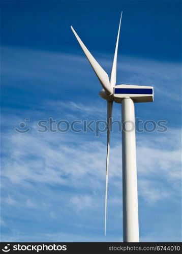 Wind turbine, wind mill. wind turbine seen from the side against blue sky with light clouds