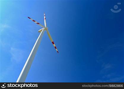 Wind turbine - windmill with blue sky background.  Concept for industry and ecology - green energy.