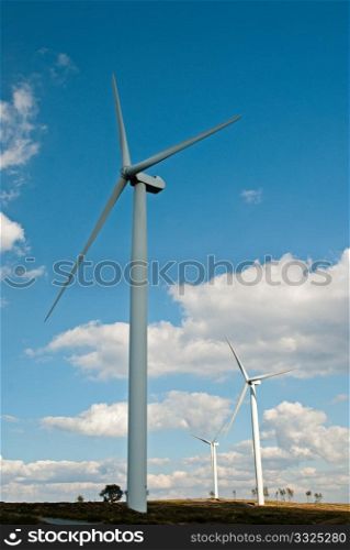 Wind turbines generating electricity with cloudy blue sky on the background.