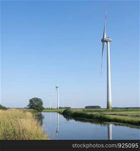 wind turbines in agriculture landscape of ostfriesland in the north of ostfriesland in lower saxony and blue sky