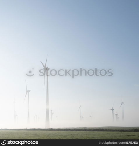 wind turbines in green meadow near aurich in german lower saxony on misty morning in august