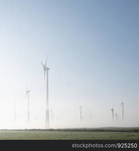 wind turbines in green meadow near aurich in german lower saxony on misty morning in august