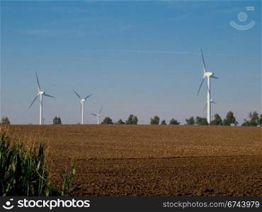 wind turbines on farmland. wind turbines on farmland with fresh field in the forground