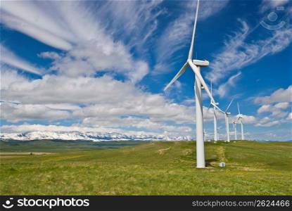 Wind turbines on grassland against cloudy sky