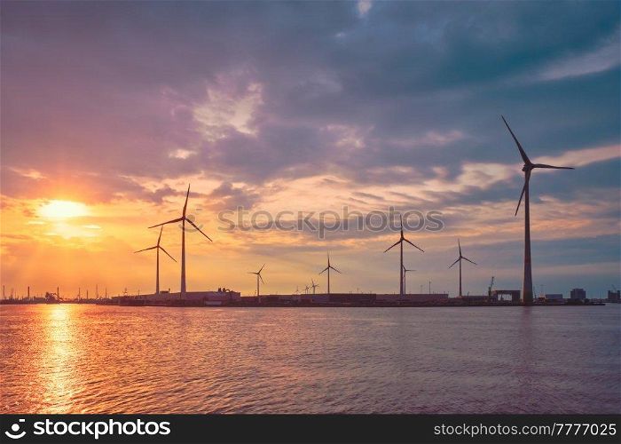 Wind turbines power electricity generators in Antwerp port on sunset. Antwerp, Belgium. Wind turbines in Antwerp port on sunset.