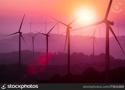 Wind turbines silhouette on mountains at sunset. Concept of renewable clean energy and sustainability development business from wind energy.