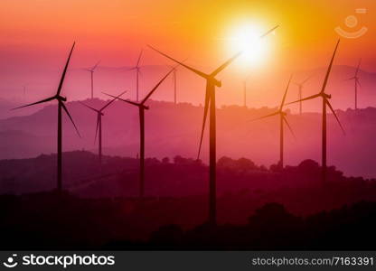 Wind turbines silhouette on mountains at sunset. Concept of renewable clean energy and sustainability development business from wind energy.