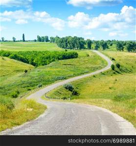 Winding asphalt road among fields in picturesque countryside.
