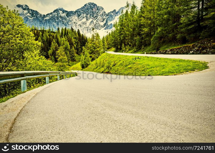 Winding asphalt road in Austrian landscape with forests, fields, pastures and meadows. Vintage style