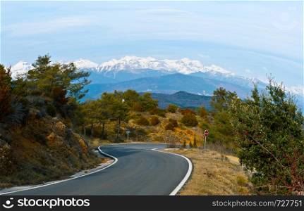 Winding asphalt road on the background of the snowy Pyrenees in Spain. Vintage style