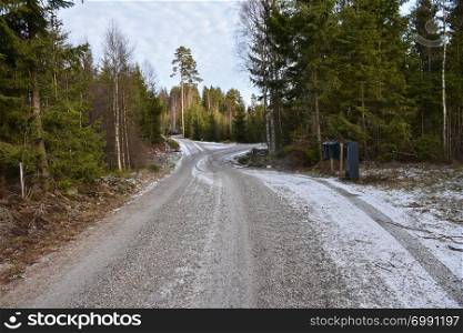 Winding gravel road with mail boxes in the woods in winter season