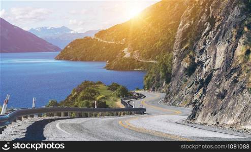 Winding road along mountain cliff and lake landscape in Queenstown, New Zealand South Island. Travel and road trip in summer.